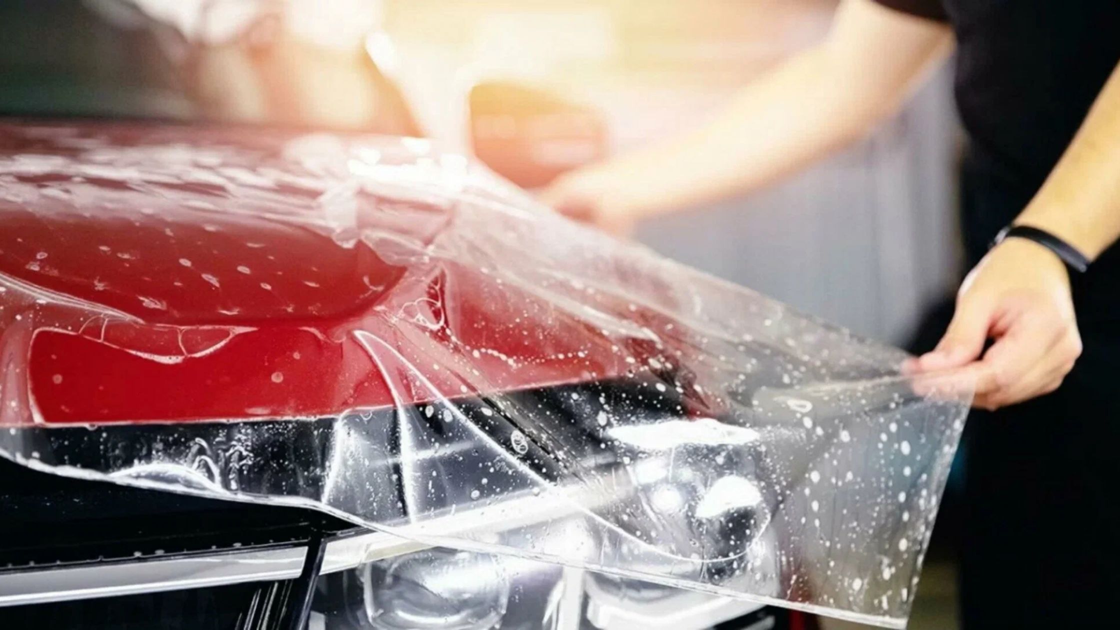 IX Exotics technician applying paint protection film on a Red car
